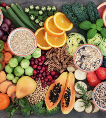 Health food concept for a high fiber diet with fruit, vegetables, cereals, whole wheat pasta, grains, legumes and herbs. Foods high in anthocyanins, antioxidants, smart carbohydrates and vitamins on marble background top view.